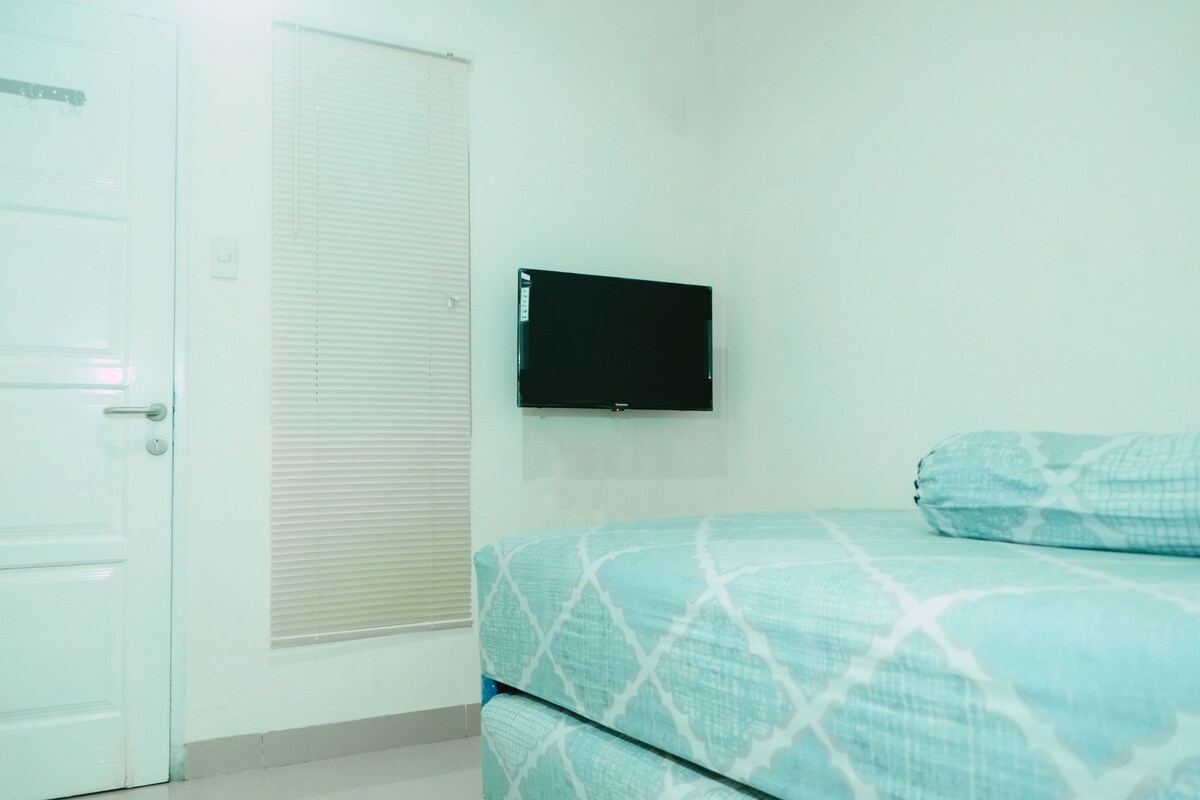 Ein Zimmer mit einem Bett, einer geschlossenen Tür und einem an der Wand befestigten Fernseher.