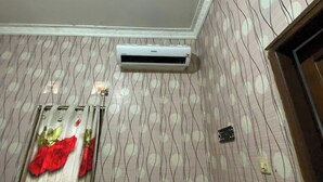 Une pièce avec un papier peint à motifs, un climatiseur fixé au mur et un élément décoratif aux couleurs rouge et verte.