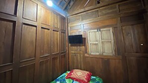Une pièce en bois avec un lit, un téléviseur à écran plat fixé au mur et une lucarne.
