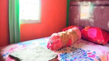 A bed with a patterned bedspread, pillows, and a notebook on it.