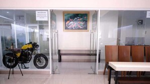 A reception area with a motorcycle on display, a bench, and a welcome mat. - Giant Kost (Gading Serpong)