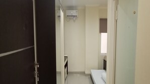 A narrow hallway leading to a bedroom with a bed and a window. - Giant Kost (Gading Serpong)
