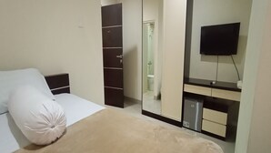 A bedroom with a bed, a wardrobe, a mirror, and a television. - Giant Kost (Gading Serpong)
