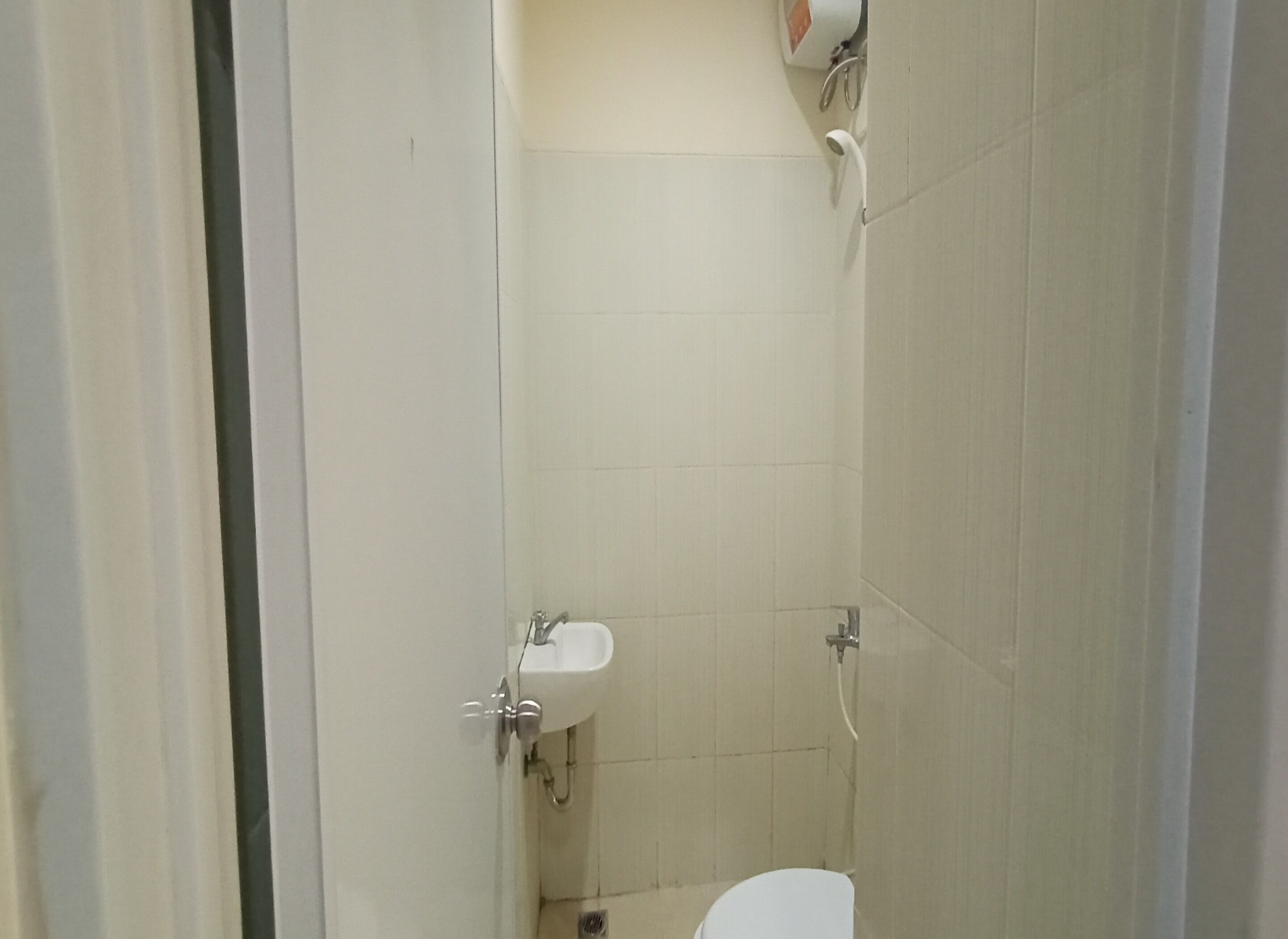 A small, enclosed bathroom with a toilet, sink, and shower.