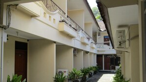 A corridor with potted plants, a tiled floor, and a staircase with a metal railing. - Hotel Family Syariah 1 (Parangtritis)