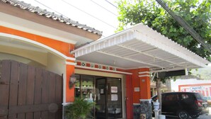 A hotel entrance with a covered porch, a wooden gate, and a parked car. - Hotel Family Syariah 1 (Parangtritis)