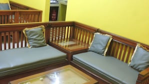 A room with two wooden sofas with cushions, a glass coffee table, and a wooden bench.