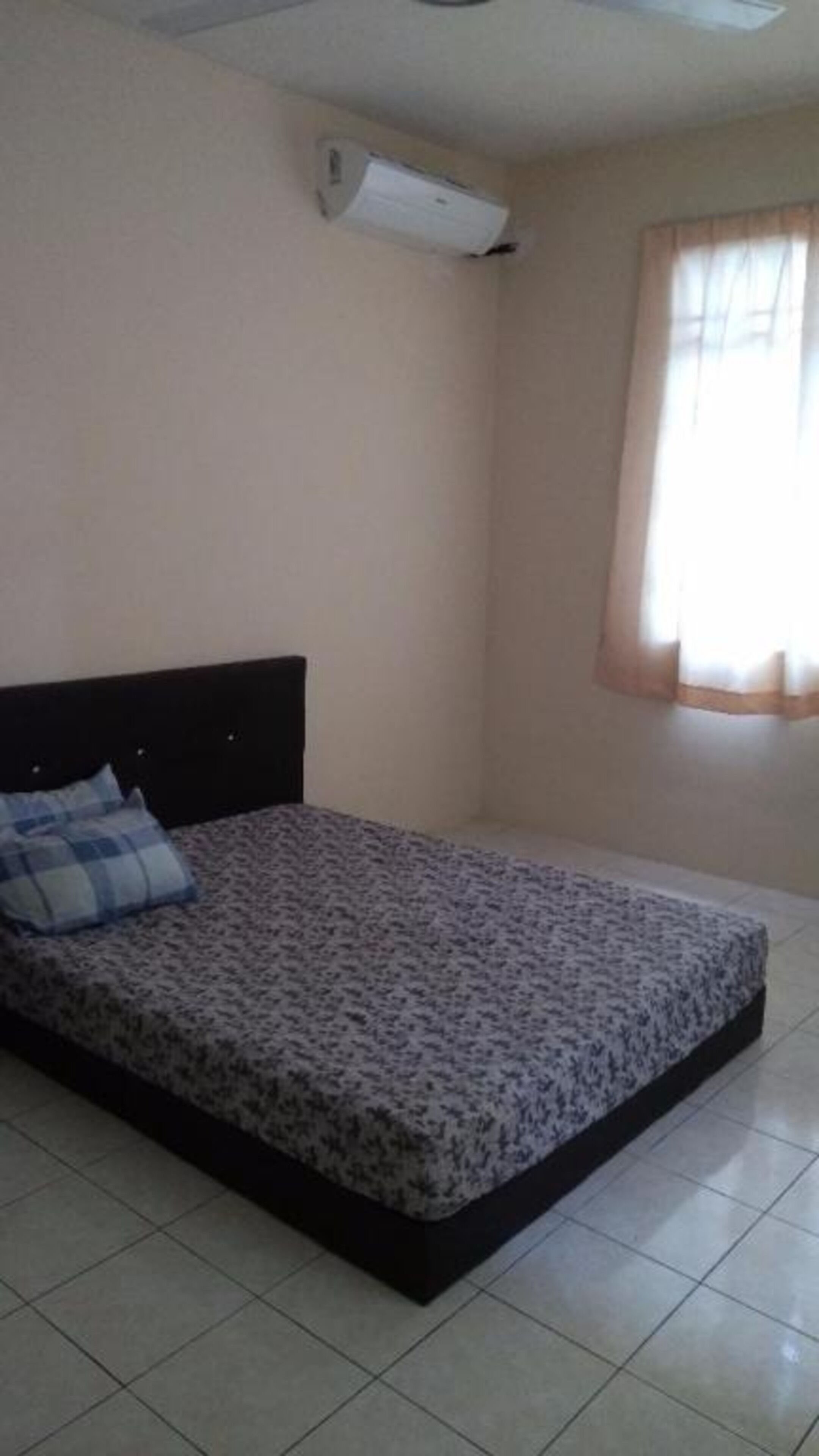 A bedroom with a bed, a ceiling fan, and a window with curtains.
