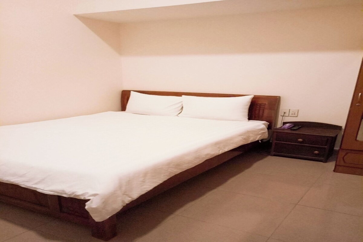 A standard hotel room with a single bed, a nightstand, and a wardrobe.