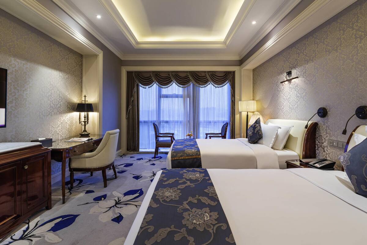 Habitación de hotel con una cama grande, un escritorio, una silla y vistas al exterior a través de una ventana.