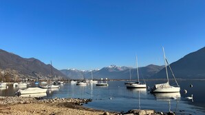 A marina with boats docked, surrounded by mountains and clear skies. - Riva Rooms & Studios (Minusio)