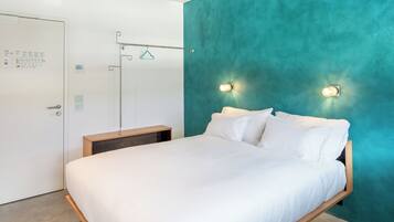 Une chambre à coucher avec un lit, une table de chevet en bois, un mur d’accent de couleur turquoise et deux lampes fixées au mur.