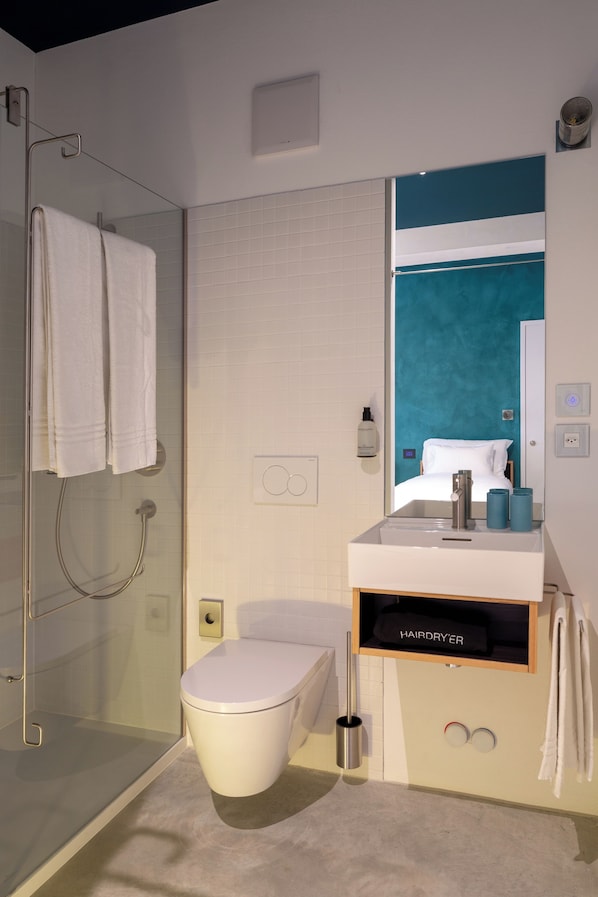 A modern bathroom with a glass shower enclosure, a toilet, and a sink with a mirror above it. - Riva Rooms & Studios (Minusio)