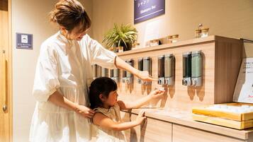 A woman and a child interacting with a shampoo bar dispenser wall.