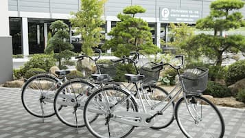 A row of bicycles parked in front of a building with a sign indicating a parking area.