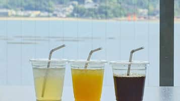 Three plastic cups with straws on a table by a window overlooking a body of water.