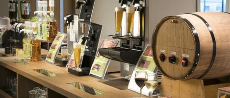 A bar area with a beer tap, various bottles, glasses, and a wooden barrel with taps.