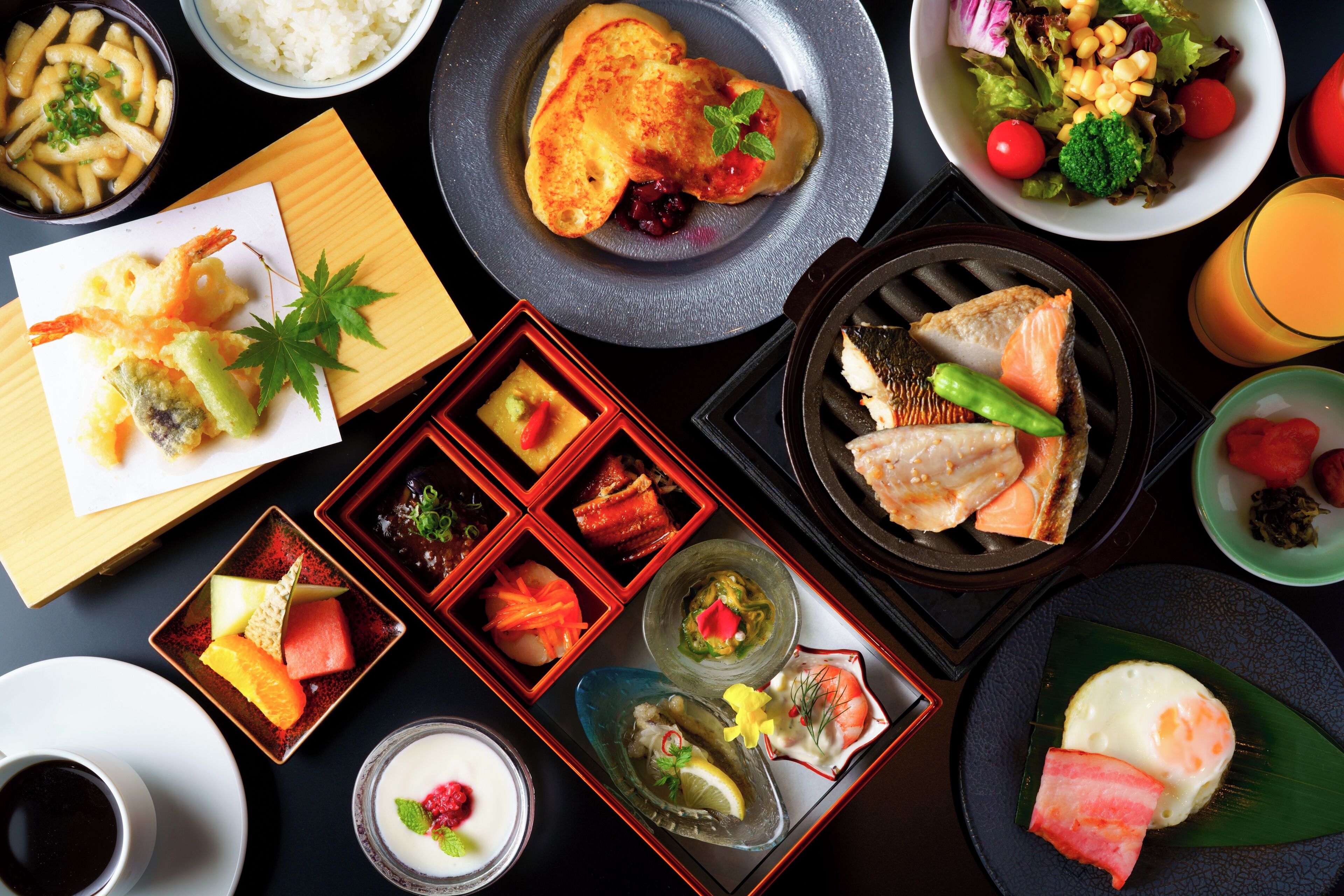 Une variété de plats japonais, notamment des beignets de tempura, du sashimi et des sushis, disposés sur une table.