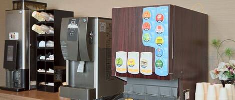 Una estación de café con una máquina de café, un dispensador de bebidas y una selección de opciones.