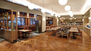 A spacious restaurant with wooden flooring, multiple dining areas, and hanging pendant lights. - Swiss-Belinn Wahid Hasyim (Jakarta)