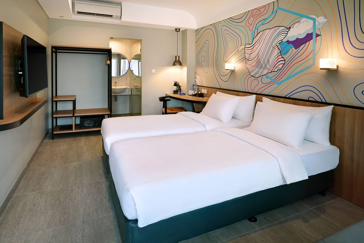 A hotel room with a large bed, a desk, a chair, a TV, and a bathroom with a mirror and sink.