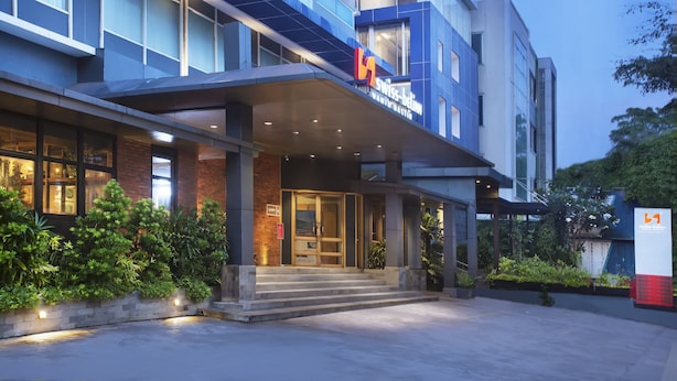 A modern hotel entrance with a glass facade, a covered entrance area, and a sign indicating it is a Swissôtel. - Swiss-Belinn Wahid Hasyim (Jakarta)