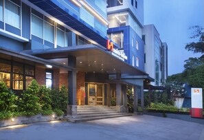 A modern hotel entrance with a glass facade, a covered entrance area, and a sign indicating it is a Swissôtel. - Swiss-Belinn Wahid Hasyim (Jakarta)