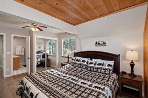 A bedroom with a bed, a nightstand, a ceiling fan, and a window.