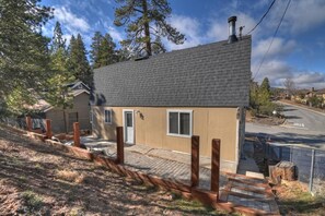 Una casa de un piso con techo inclinado, una chimenea y un pequeño porche con columnas de madera.