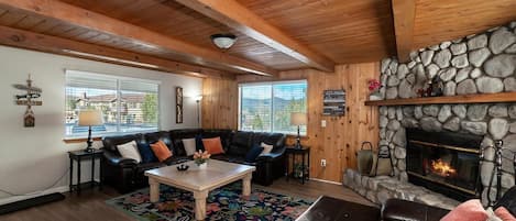 A cozy living room with a stone fireplace, wooden ceiling beams, and a leather sofa.