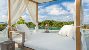 A bed with white linens and a canopy, set against a backdrop of a clear sky and lush greenery. - Vrysomylos - Unique Villa on the beach front (Gargalianoi)