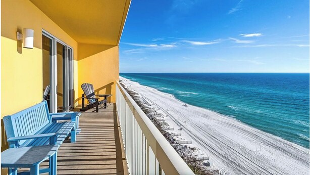 A balcony with blue chairs, a wooden deck, and a view of the beach and ocean. - Calypso 1005E - Gulf-Front Luxury, Beach Svc Included, Pier Park, Sleeps 4 (Panama City Beach)