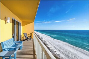 Een balkon met blauwe stoelen, een houten terras en uitzicht op het strand en de oceaan.
