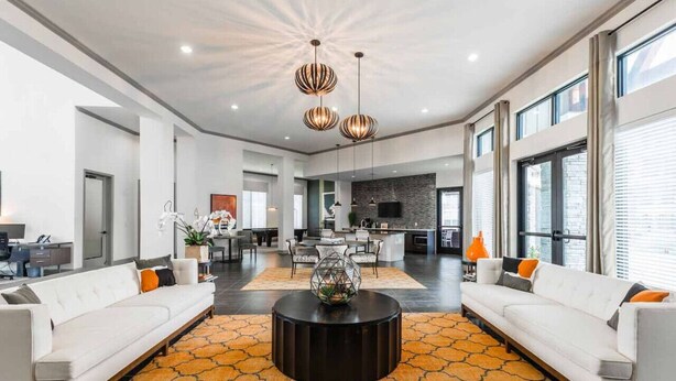 A spacious living area with a modern design, featuring a central coffee table, two sofas, and a kitchen in the background. - Fully Furnished Pool View Apartment in Tomball, TX (Tomball)