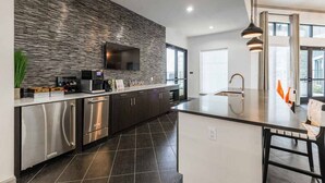 A modern kitchen with a stone backsplash, stainless steel appliances, and a large island with a sink. - Fully Furnished Pool View Apartment in Tomball, TX (Tomball)
