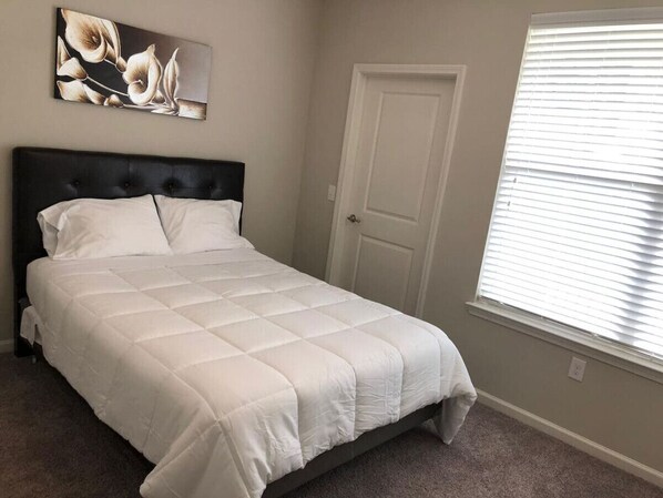 Une chambre à coucher avec un lit, une porte et une fenêtre équipée de stores.