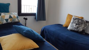 A bedroom with two beds, each with a blue bedspread and pillows in yellow and blue.