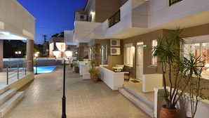 Un hotel moderno con piscina, mobiliario exterior y plantas en macetas.