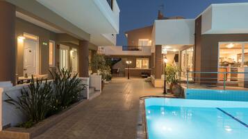Una piscina al aire libre, sombrillas, sillones reclinables de piscina