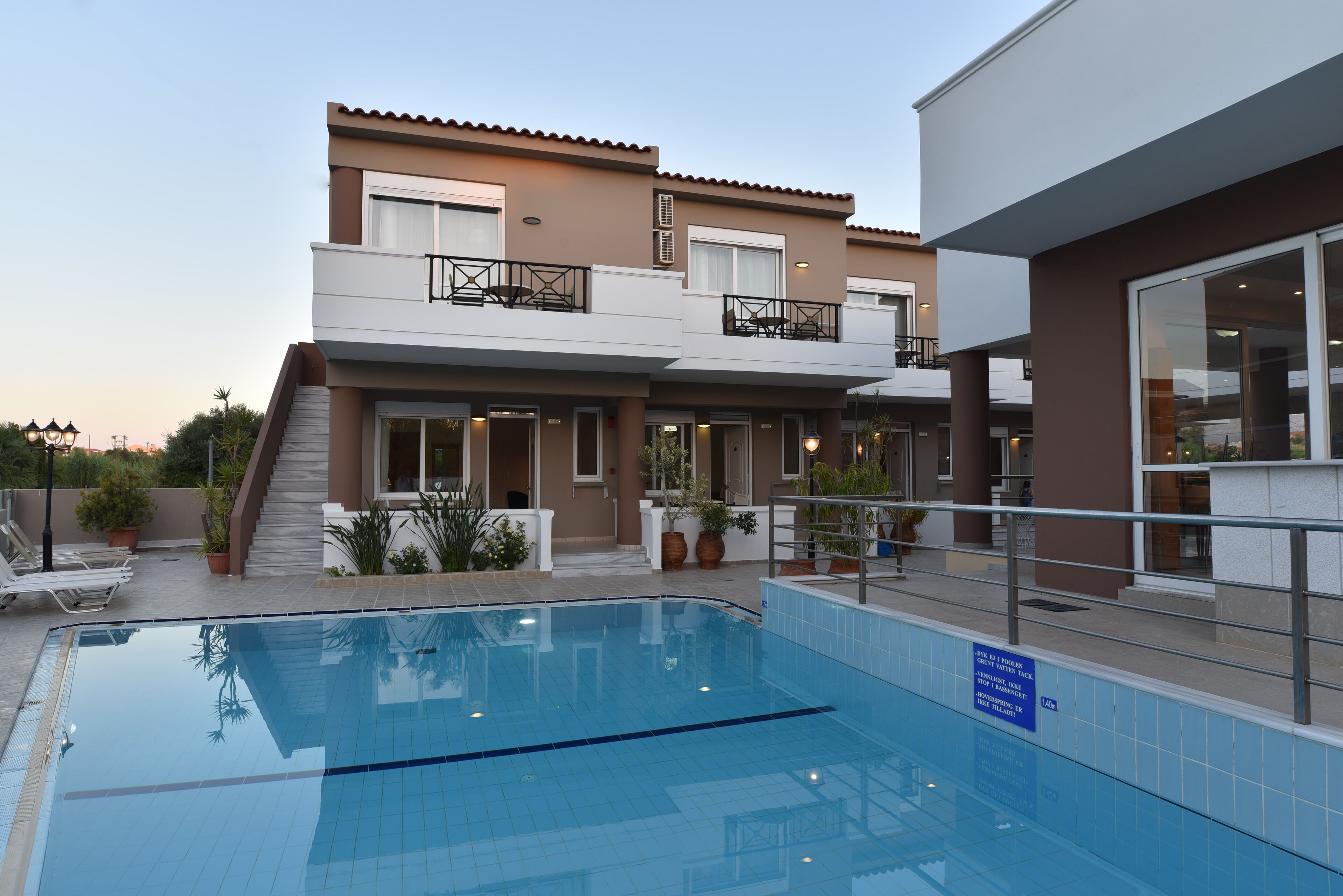 Un hotel moderno con piscina, balcones y un área exterior bien cuidada.