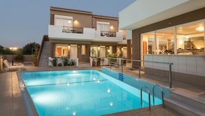 Un edificio moderno de dos pisos con piscina, mobiliario exterior y una escalera que lleva al piso superior.