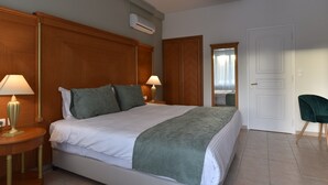 Una habitación de hotel con una cama grande, dos lámparas de noche, un espejo y una puerta.