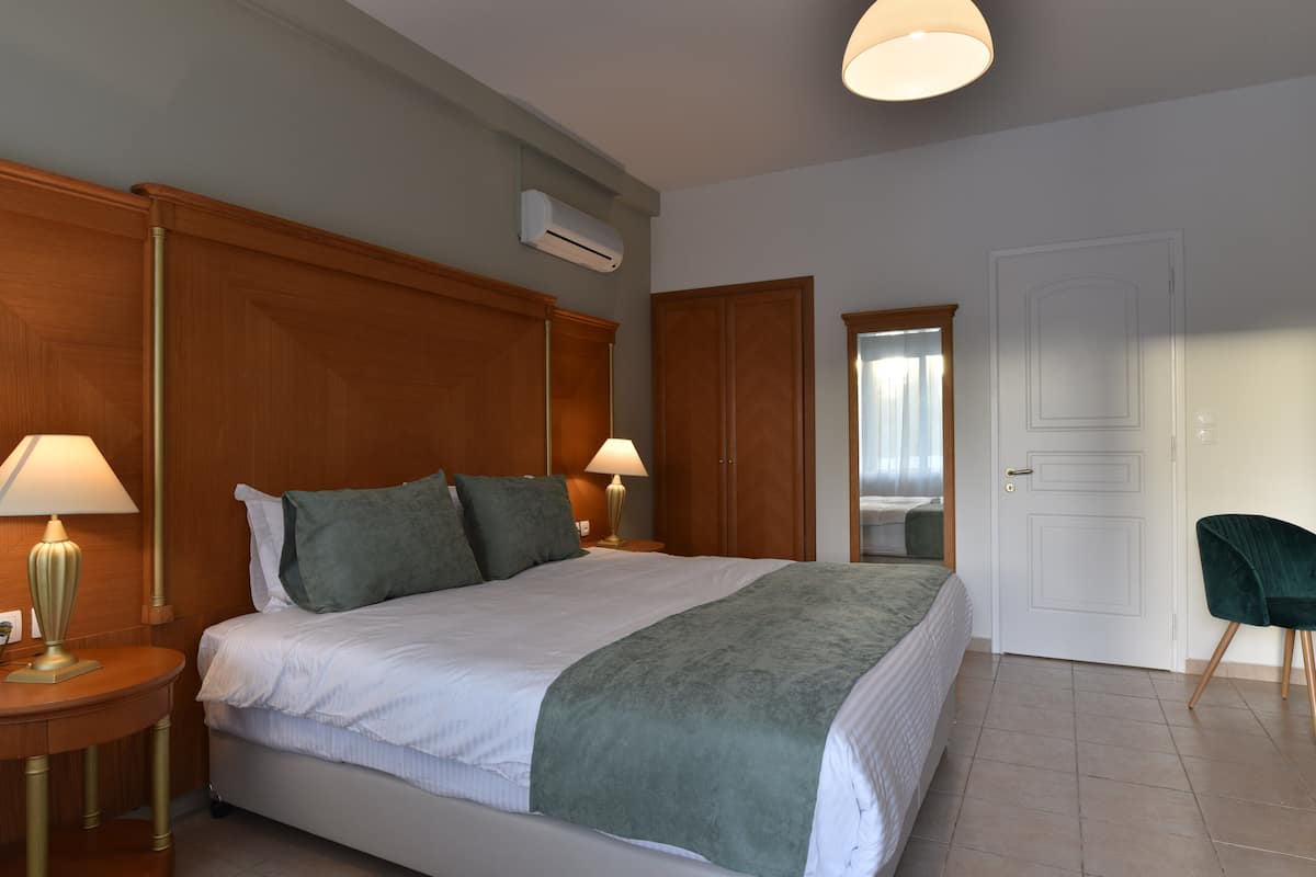 A hotel room with a large bed, two bedside lamps, a mirror, and a door.