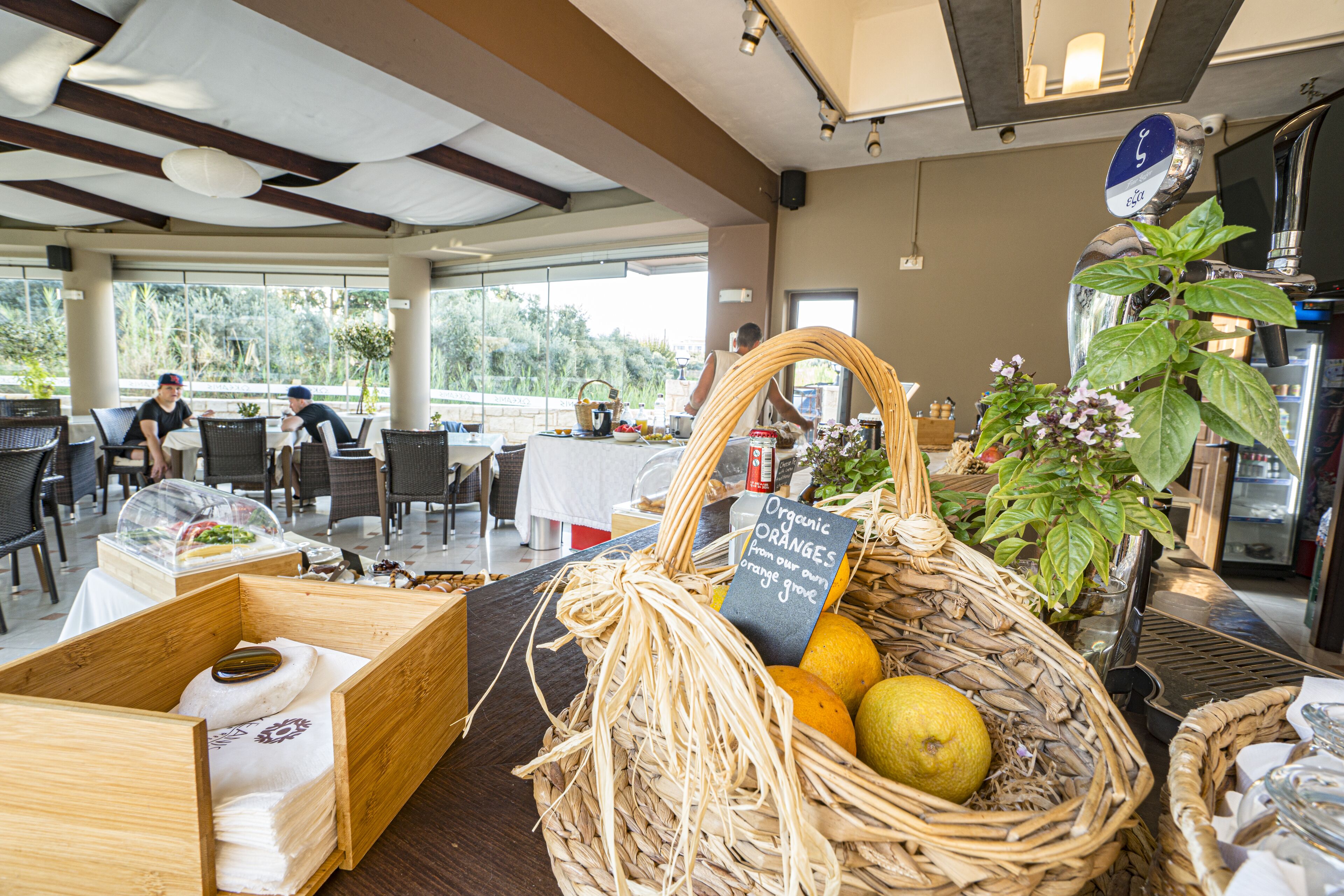 Un restaurante con terraza, cestas de mimbre con frutas y un cartel que indica naranjas orgánicas.