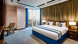 A hotel room with a large bed, a chair, a nightstand, and a view of the city through a large window. - Al Malqa Elite Hotel (Riyadh)