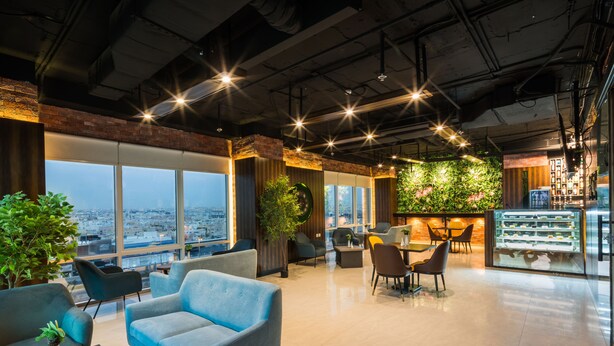 A modern lounge area with seating, a dessert display, and a view of the city. - Al Malqa Elite Hotel (Riyadh)