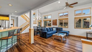 Ein geräumiger Wohnbereich mit Holzboden, einem blauen modularen Sofa, einem Couchtisch und einer Küchenzeile mit Bar und Hockern.