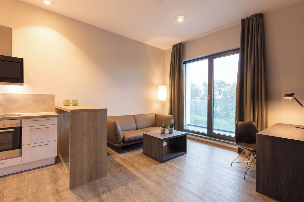 Una sala de estar moderna con un sofá, una mesa de centro y una pequeña zona de cocina con estufa.