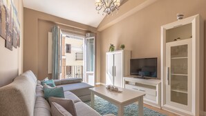 Un salon comprenant un canapé, un téléviseur, un meuble et donnant sur l’extérieur.
