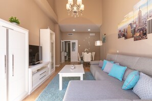 A modern living room with a sofa, TV, white cabinet, and a cityscape painting. - Holiday Apartment “Sofía Ronda Center” with Terrace, Air Conditioning & Wi-Fi (Ronda)